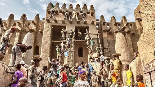 Thousands rebuilding the Great Mosque of Djenne, under threat from conflict in Mali