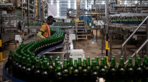 A worker monitors newly bottled beers on the production line at the InBev beer factory in Ogun State, outside Lagos, on November 7, 2018. [Photo by STEFAN HEUNISAFP via Getty Images]